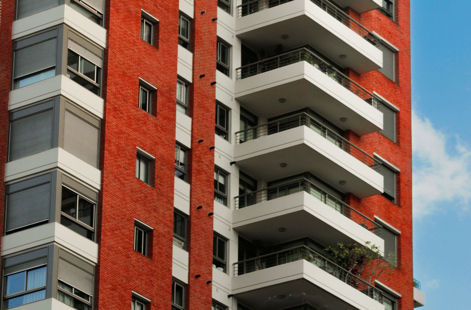 A red brick apartment building with balconies, the home behind a tenant's email