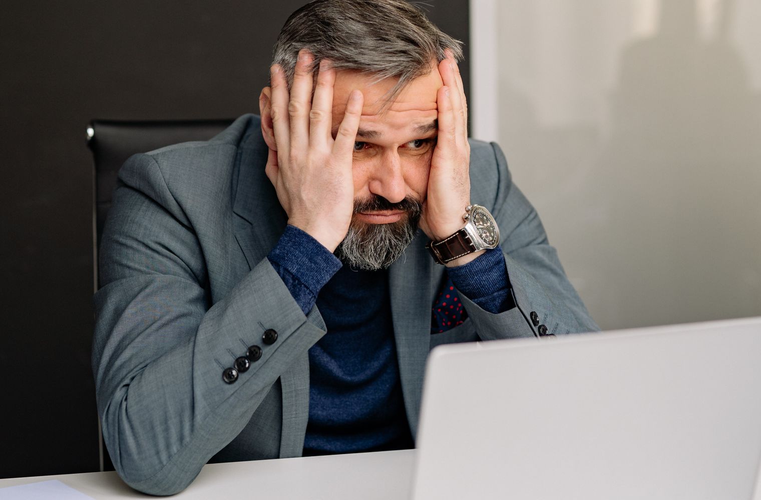 A property manager at a laptop with his hands on his face after reading an angry tenant email