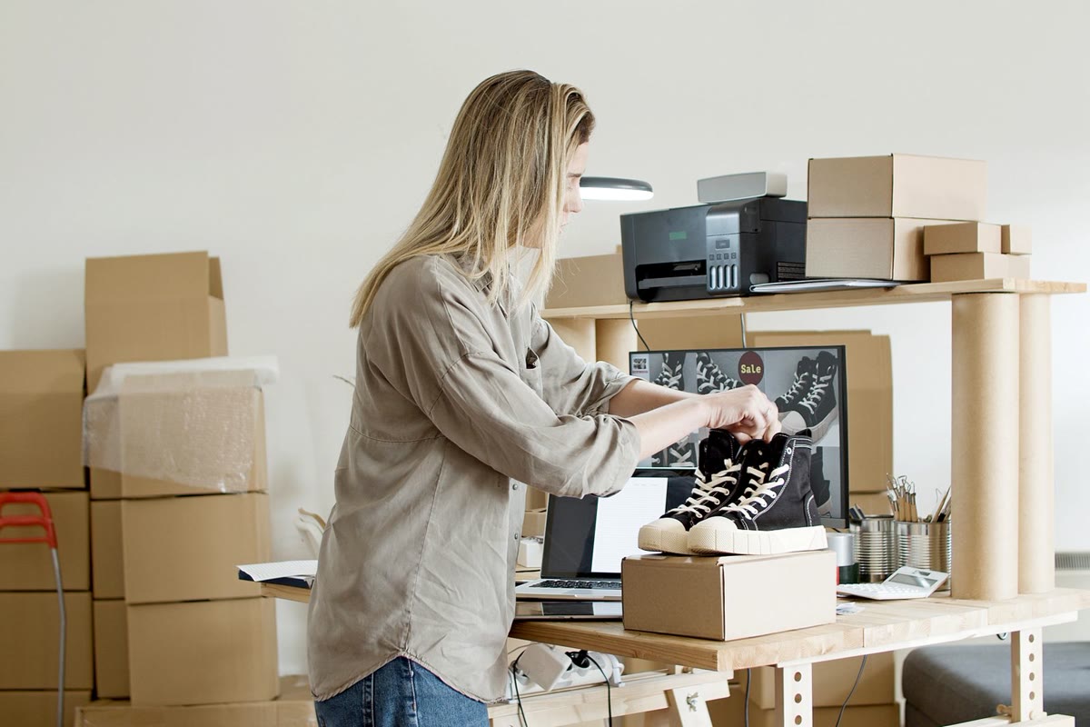 A small brand owner packing wholesale orders at a workbench with boxes and product