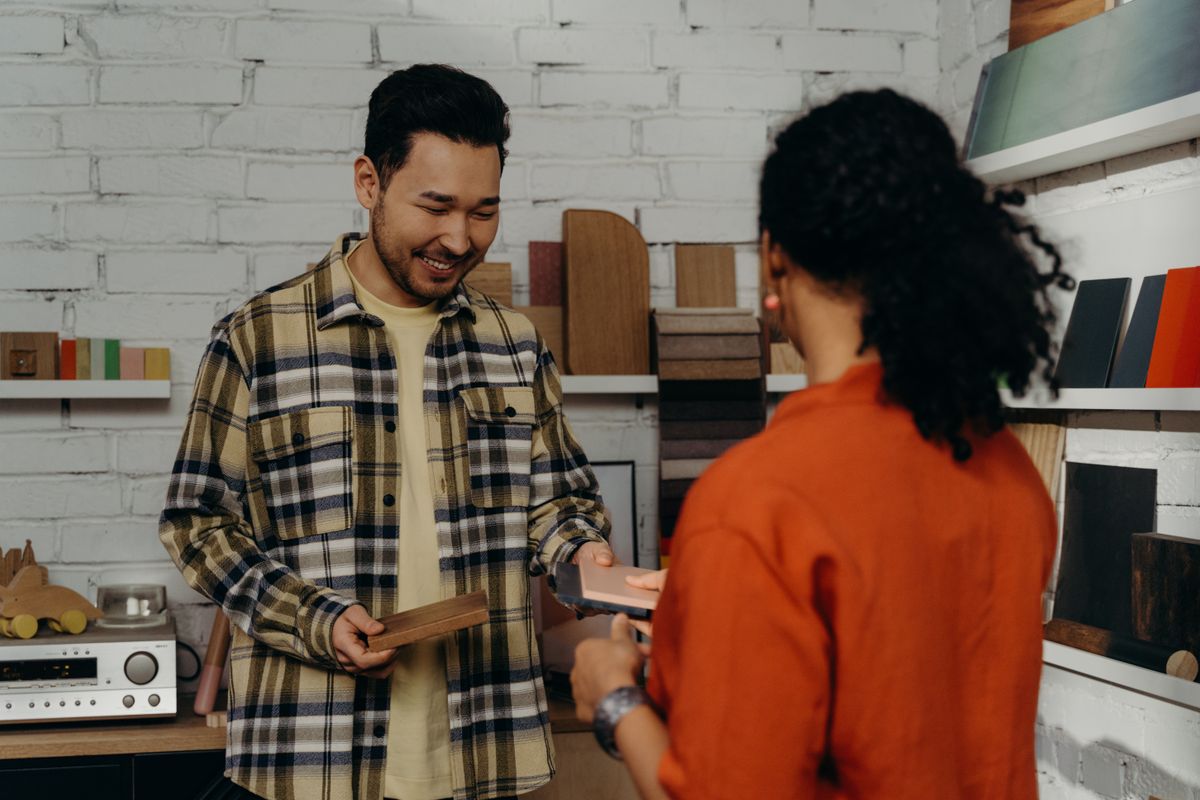 A maker showing wood samples to a customer in a small showroom