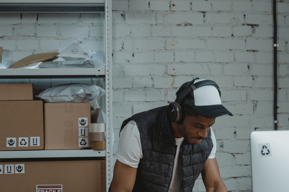 A man wearing a headset works at a desk beside shelves of labelled freight boxes