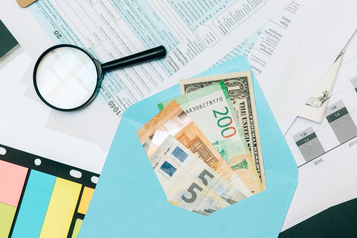 Mixed euro and dollar notes in an envelope over international paperwork