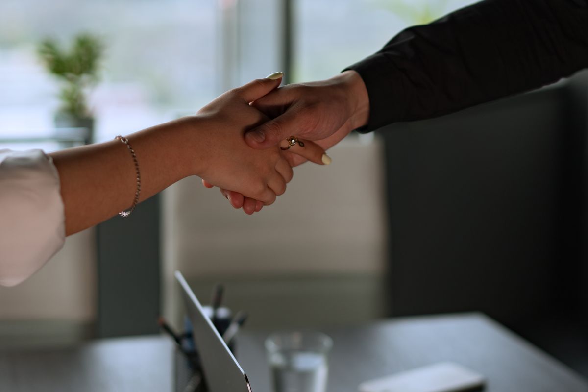 A handshake across an office desk, parting on good terms