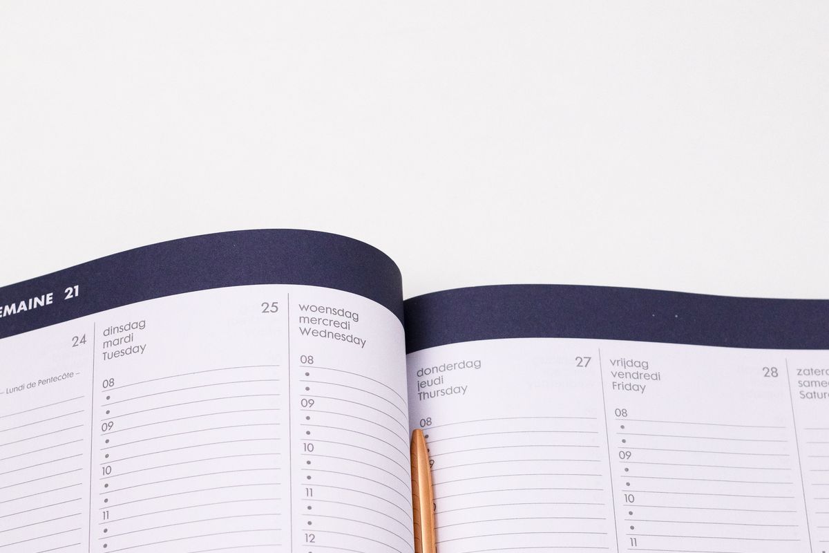 An open weekly appointment diary with a pen resting between the pages