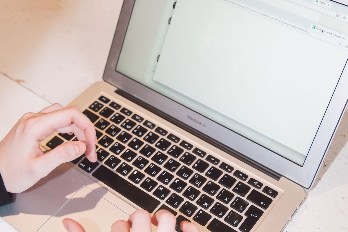Hands typing on a laptop keyboard with a browser window open on the screen