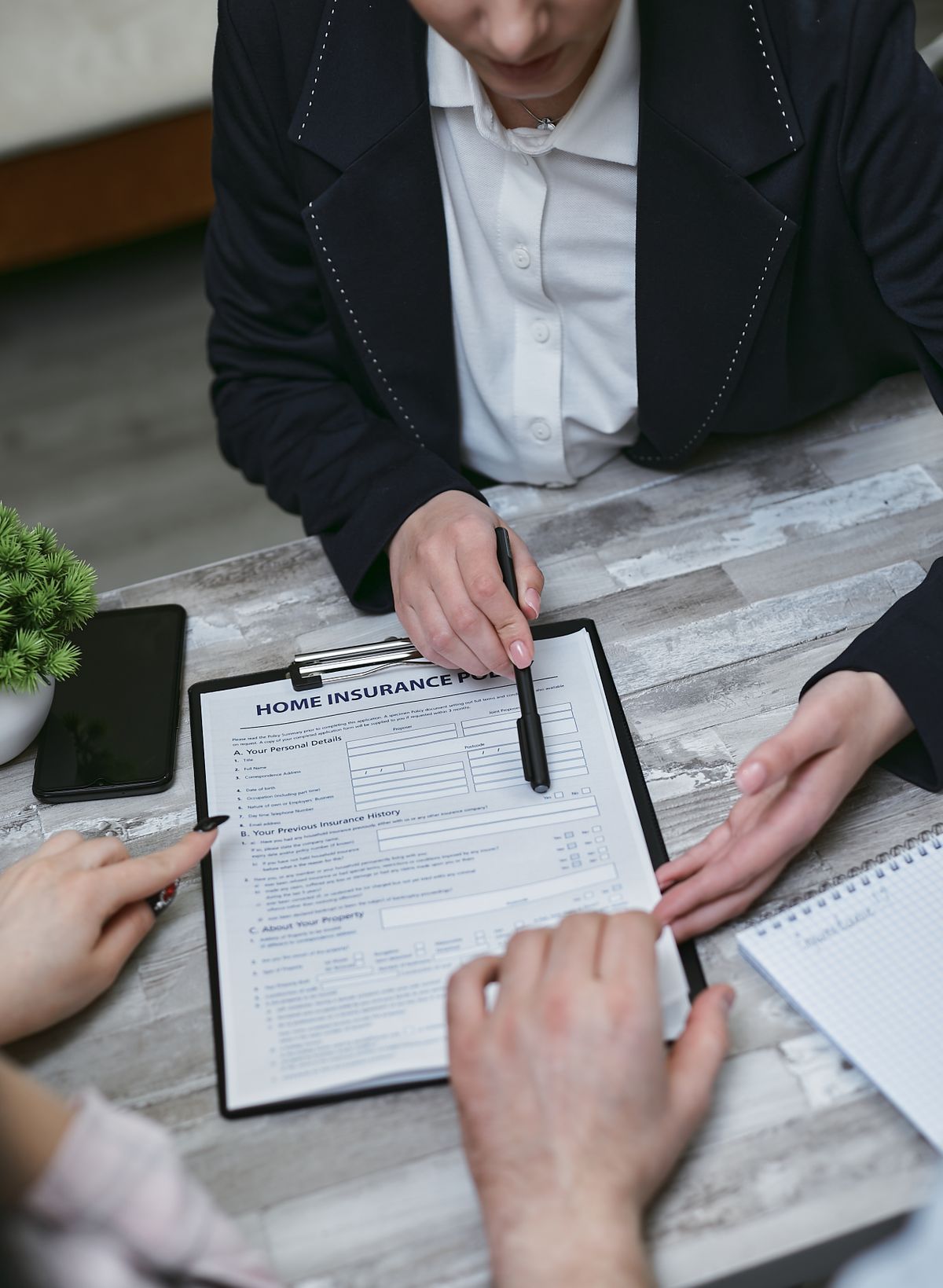 An insurance broker going through policy paperwork with two clients at a meeting table