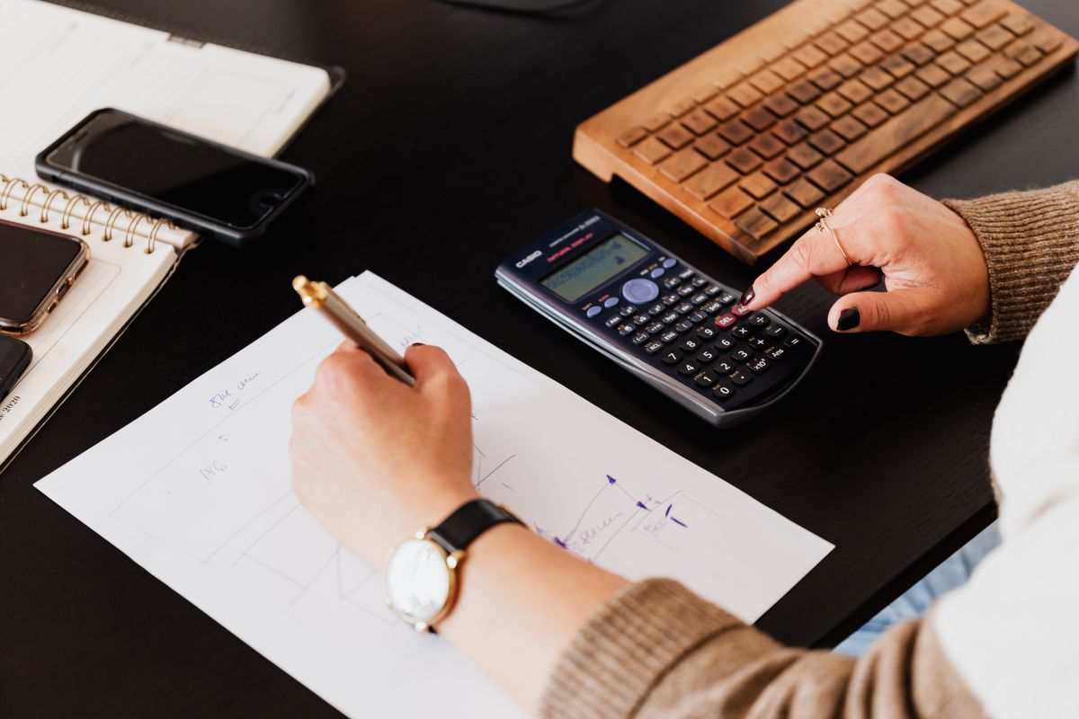 A bookkeeper works through figures with a calculator and handwritten notes