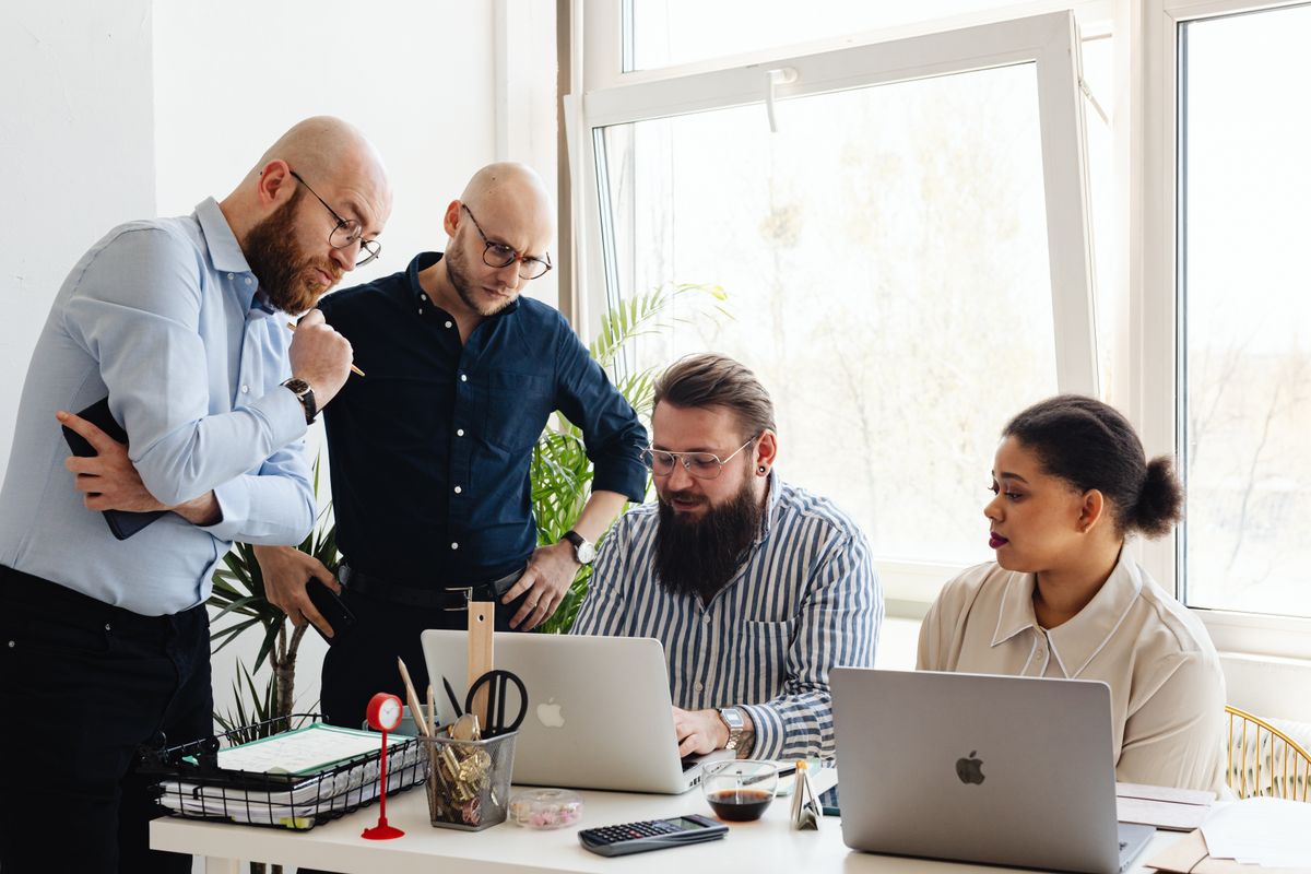A small team gathered around a laptop at a shared desk