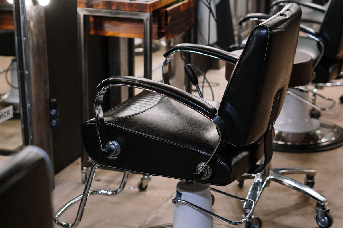 An empty barber chair waiting in a salon, mirrors lit and nobody in the room