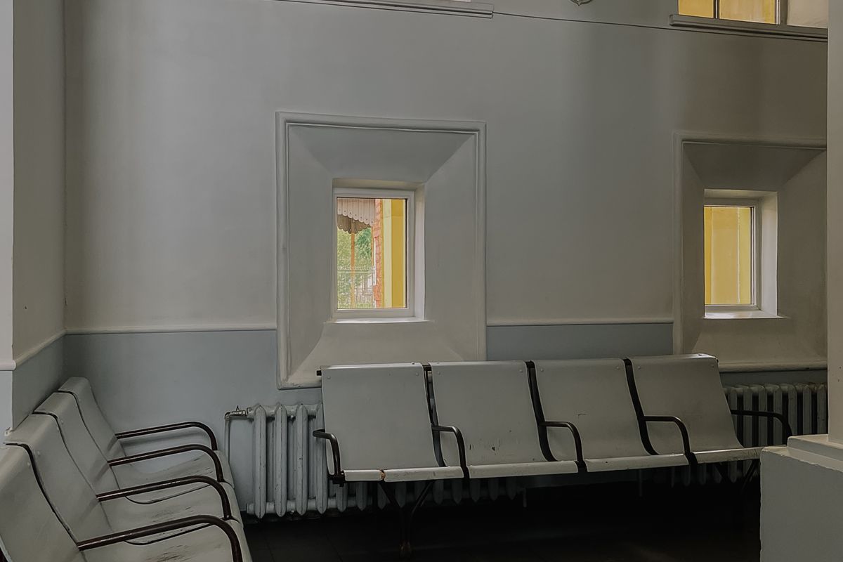 A quiet waiting room with empty metal-framed chairs and daylight from tall windows