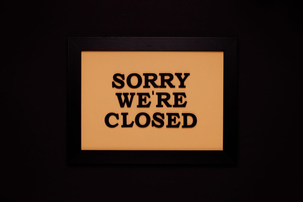 A framed sorry we are closed sign on a dark wall
