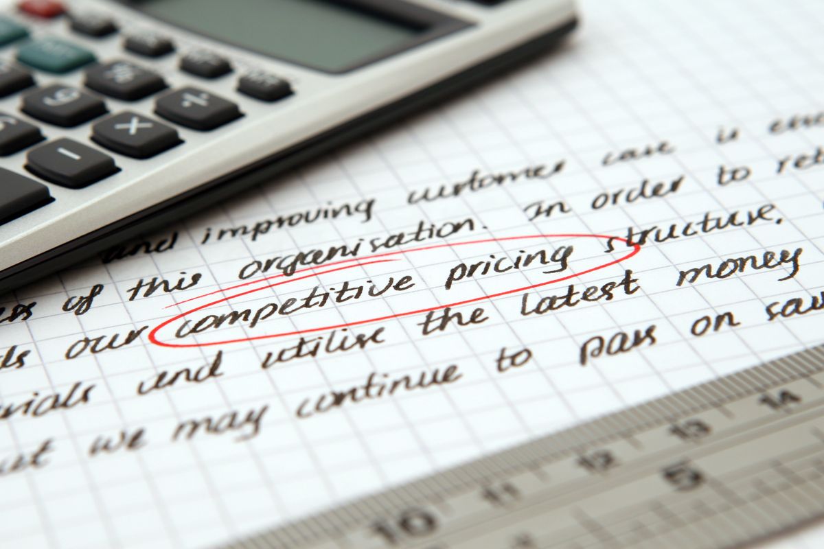 A calculator and ruler on handwritten pricing notes with the words competitive pricing circled in red