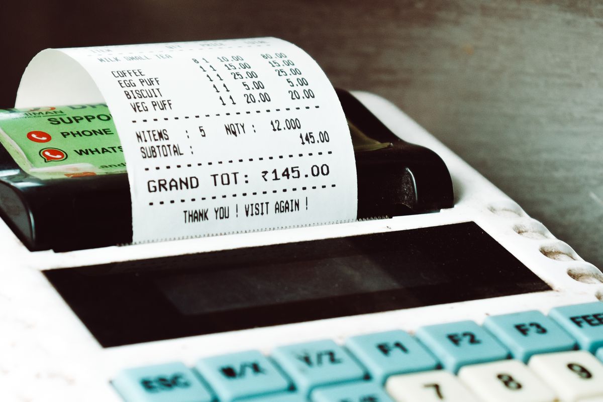 A shop till printing an itemised receipt at a small store counter