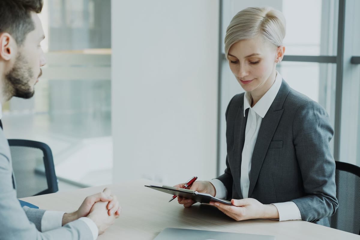 A recruiter interviewing a candidate across a desk in a bright office