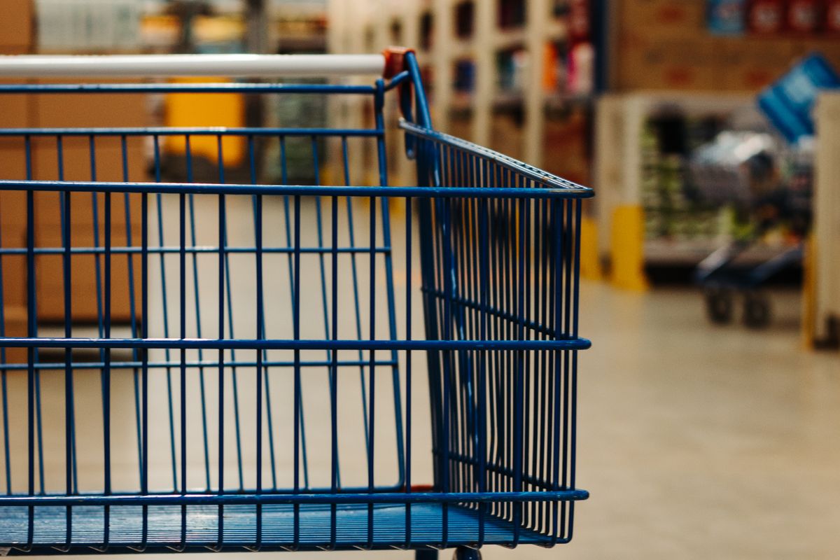 An empty blue shopping trolley in a warehouse store aisle