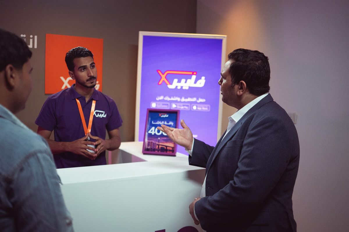 An exhibitor talks with visitors at a trade show booth