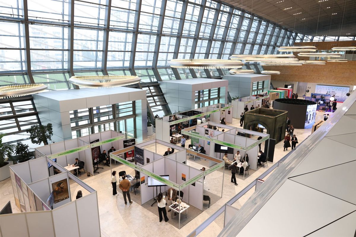 A busy exhibition hall with rows of trade show booths and visitors