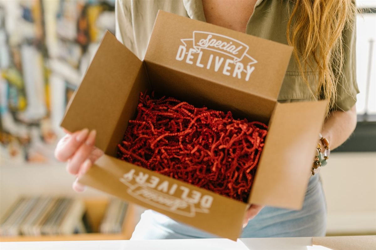 A customer opens a delivery box filled with red packing paper