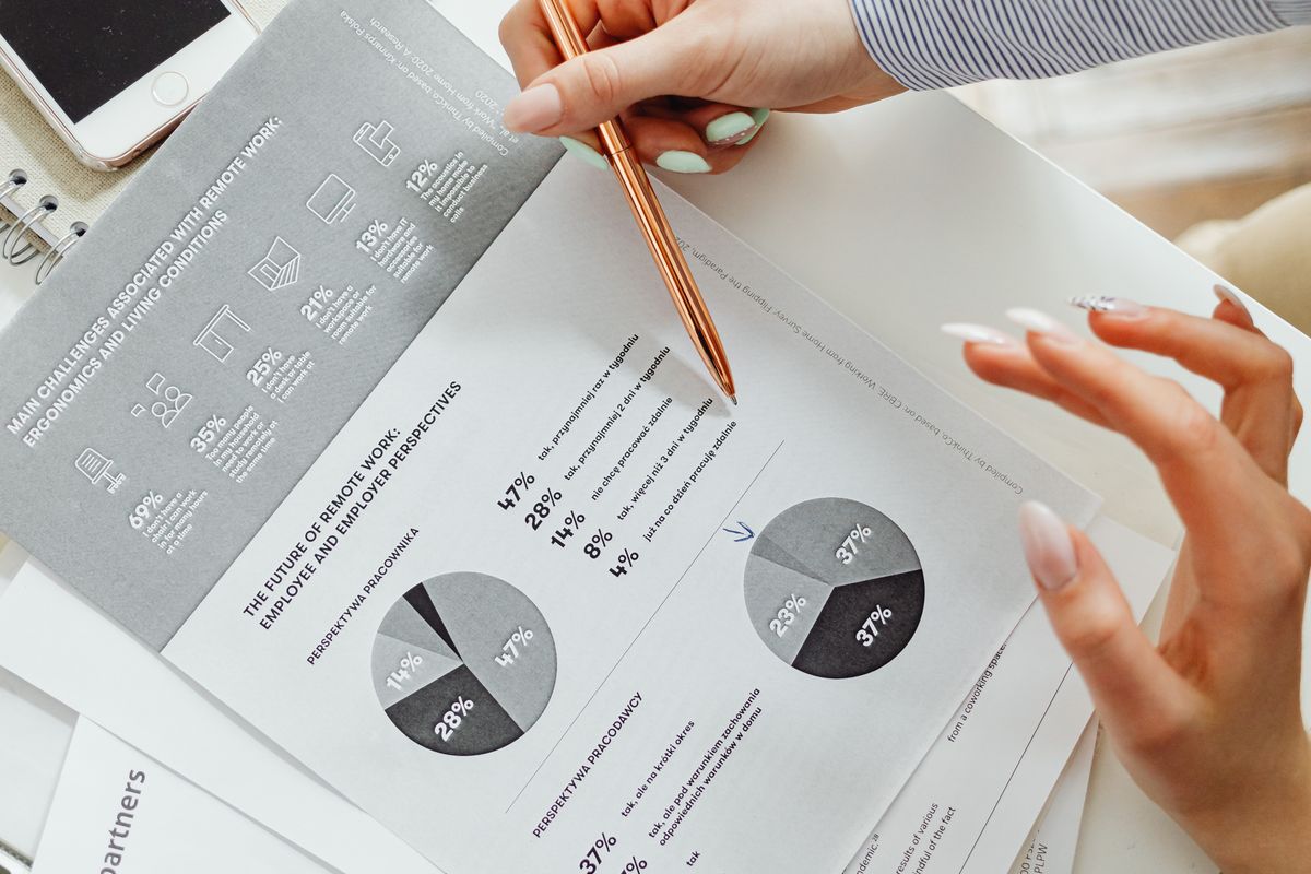 Hands reviewing a printed report with charts, pen hovering over the figures