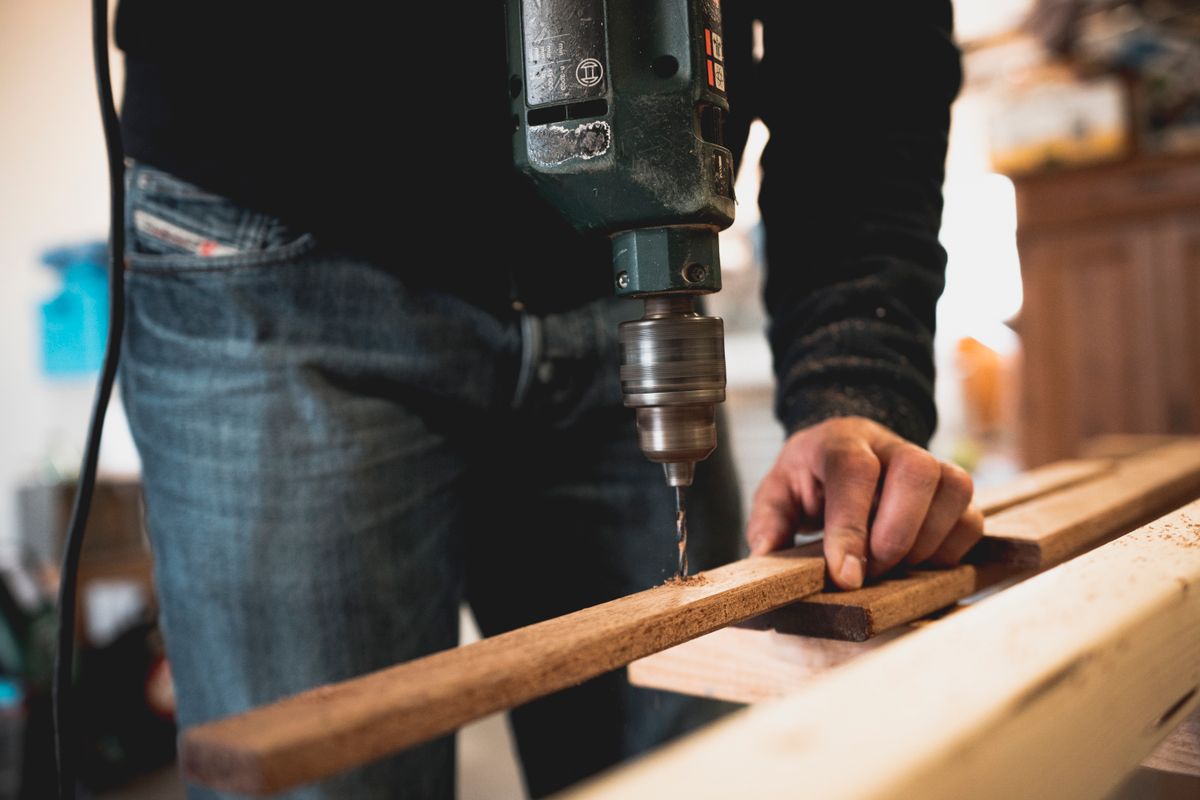 A joiner drilling a timber batten at a workshop bench