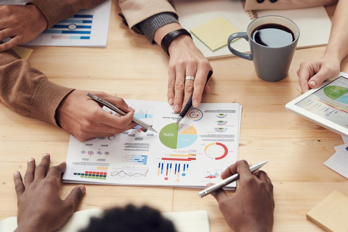 A team reviews charts and reports spread across a wooden table