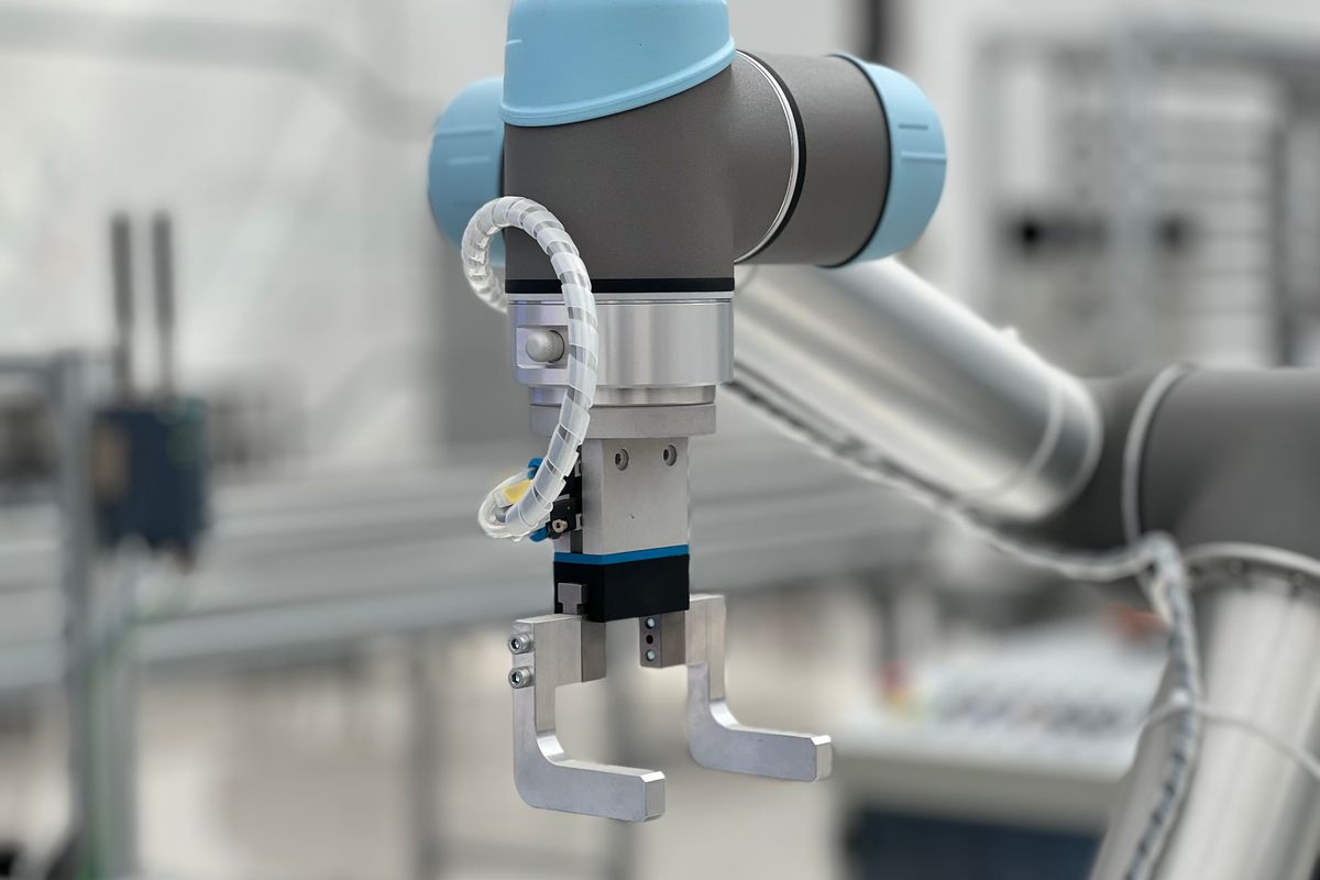 A robotic arm with a metal gripper in a clean industrial workspace