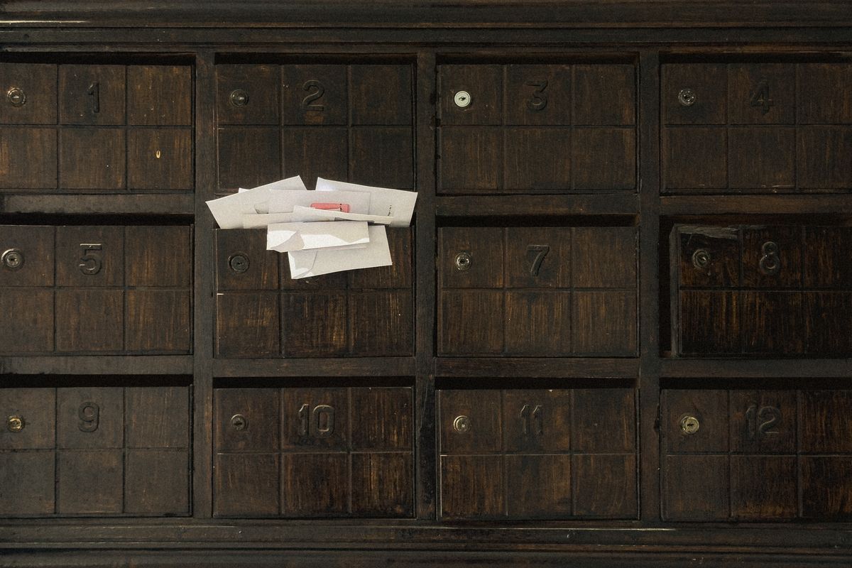 A wall of numbered wooden pigeonholes with letters stuffed into one of them