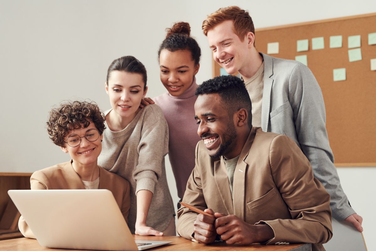 A support team gathered around a laptop in a bright office